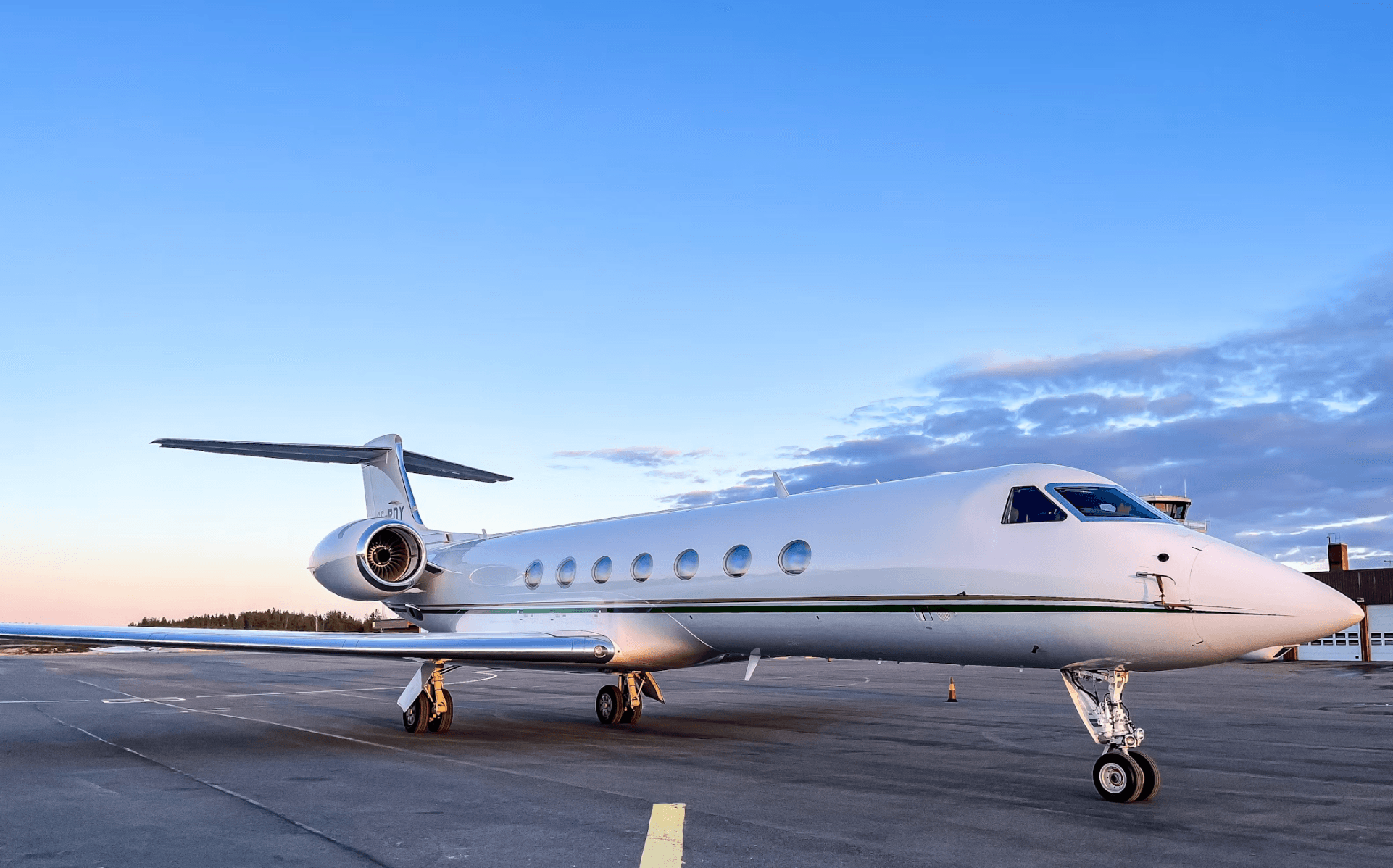 Private jet parked on the ramp at dusk under a blue sky